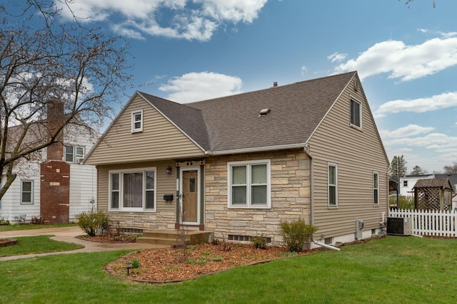 view of front of property featuring fence, a shingled roof, a front lawn, and stone siding