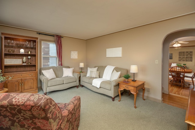 carpeted living area featuring arched walkways, baseboards, and visible vents