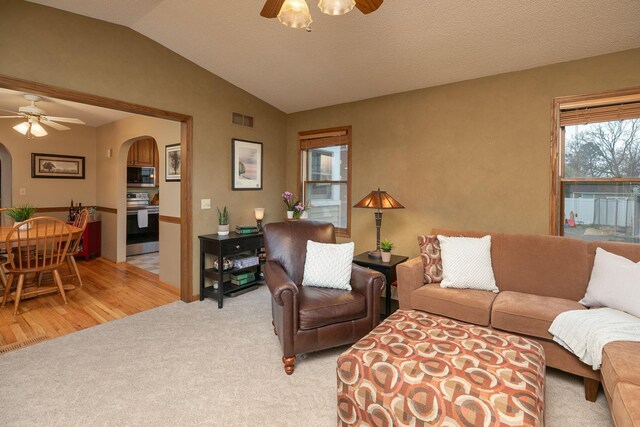 living room with arched walkways, a ceiling fan, lofted ceiling, and visible vents