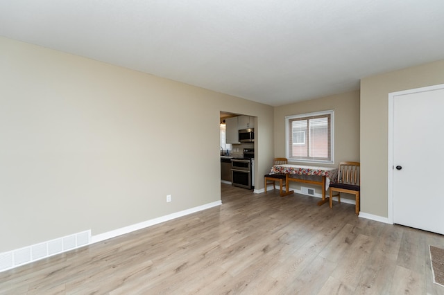 spare room with baseboards, visible vents, and light wood-style floors