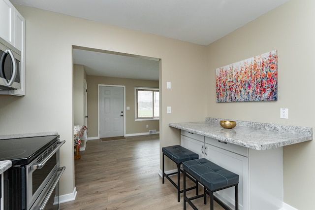 interior space with light countertops, baseboards, appliances with stainless steel finishes, and light wood-type flooring