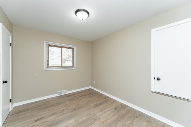 spare room featuring visible vents, light wood finished floors, and baseboards