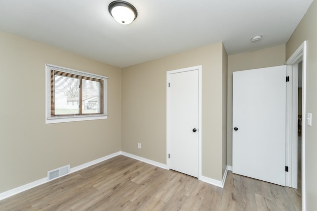 unfurnished bedroom featuring baseboards, visible vents, and light wood-style floors