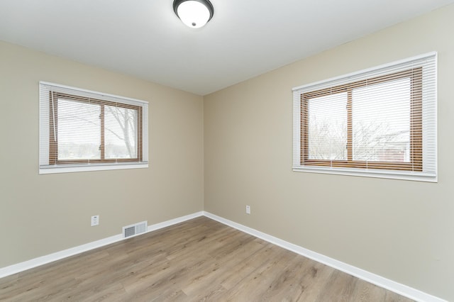 unfurnished room featuring a healthy amount of sunlight, baseboards, light wood-style floors, and visible vents