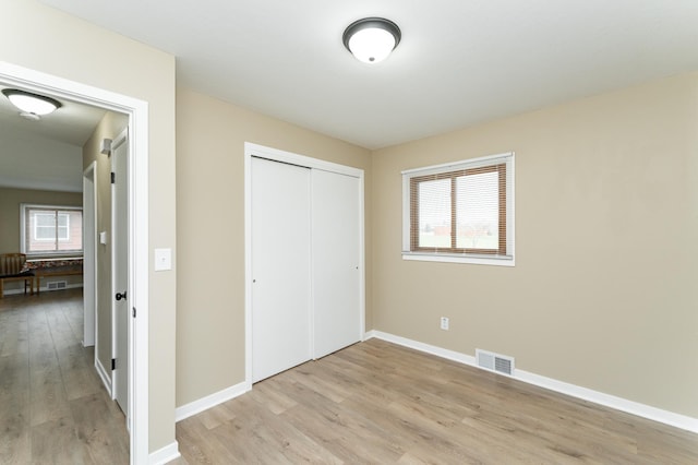 unfurnished bedroom featuring a closet, baseboards, visible vents, and light wood-type flooring