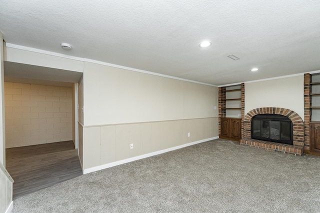 unfurnished living room with carpet floors, a textured ceiling, crown molding, and a fireplace