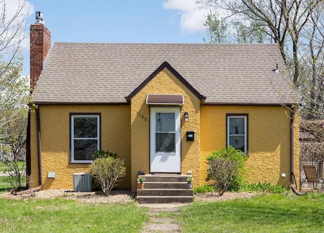 1100 Summit Ave, Saint Paul Park, MN 55071 - english style home with entry steps, a chimney, central air condition unit, stucco siding, and a shingled roof