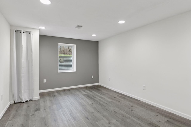 spare room featuring baseboards, recessed lighting, wood finished floors, and visible vents