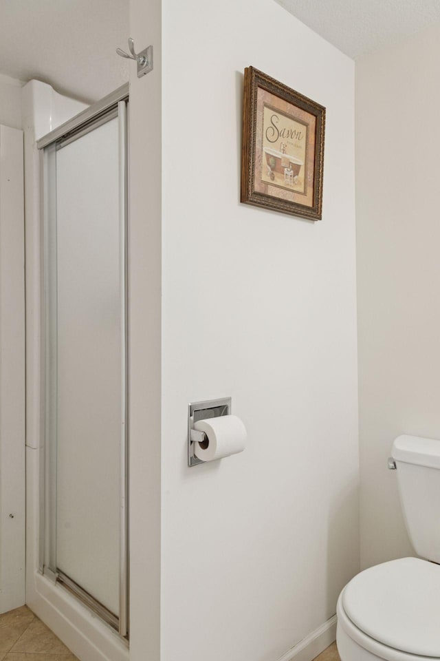 bathroom featuring tile patterned floors, toilet, and a shower stall