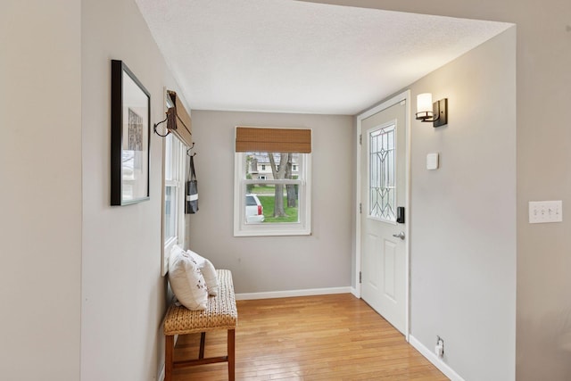 entryway featuring a textured ceiling, baseboards, and light wood-style floors
