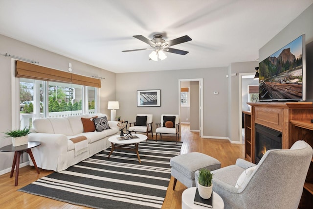 living area with a glass covered fireplace, a healthy amount of sunlight, and wood finished floors