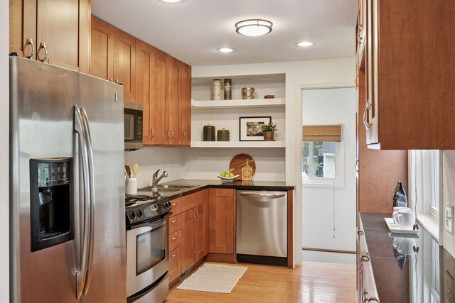 kitchen with brown cabinetry, open shelves, a sink, light wood finished floors, and appliances with stainless steel finishes