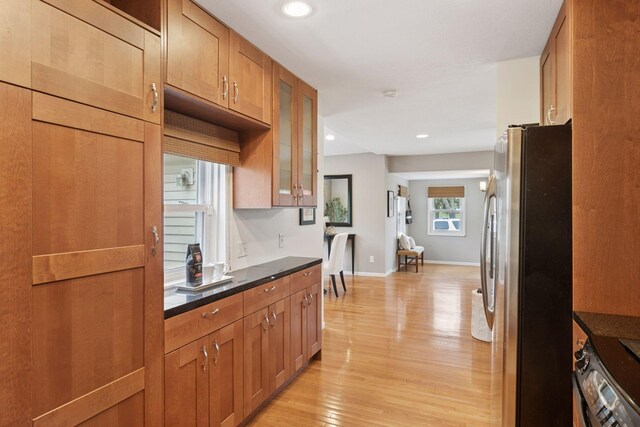 kitchen with light wood-style floors, brown cabinets, freestanding refrigerator, glass insert cabinets, and recessed lighting
