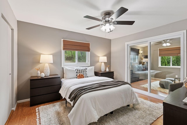 bedroom featuring light wood-type flooring, multiple windows, baseboards, and a closet