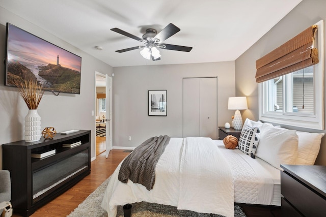 bedroom with baseboards, a ceiling fan, a closet, and wood finished floors