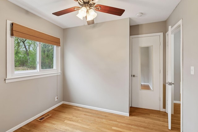 spare room with ceiling fan, baseboards, visible vents, and light wood-style flooring