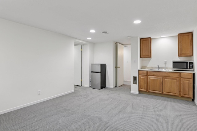 kitchen with visible vents, light colored carpet, light countertops, a sink, and appliances with stainless steel finishes