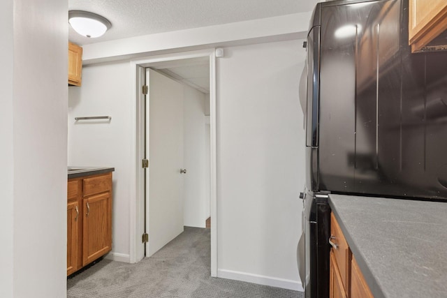 interior space featuring baseboards, freestanding refrigerator, brown cabinetry, and light carpet