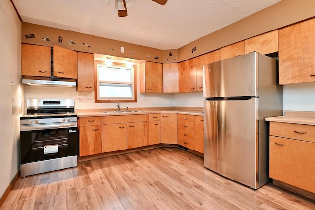 kitchen with a sink, stainless steel appliances, light wood-type flooring, and under cabinet range hood