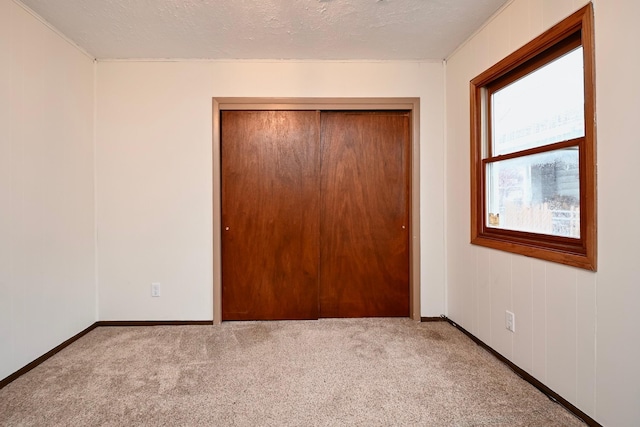 unfurnished bedroom featuring a closet, baseboards, and carpet flooring