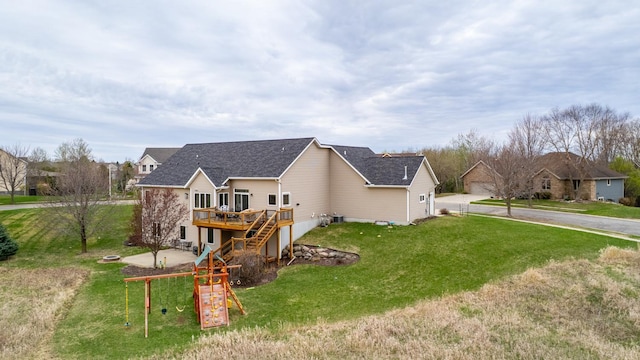 rear view of property featuring a yard, a wooden deck, and roof with shingles
