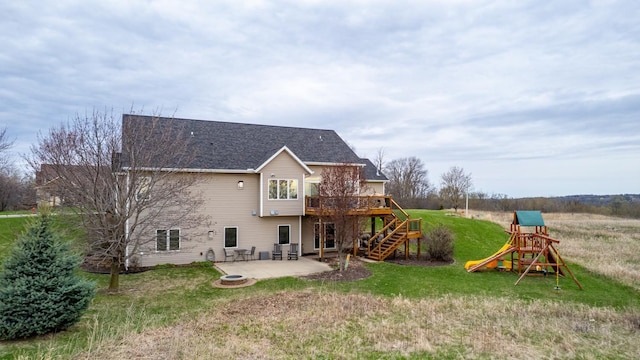 back of house with a deck, a playground, a patio area, a lawn, and stairway