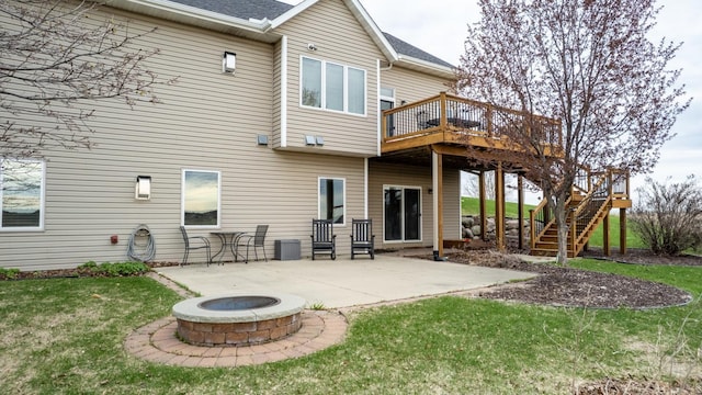 rear view of house with a deck, stairway, a patio area, a lawn, and a fire pit