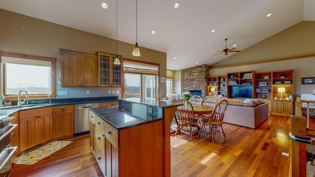 kitchen with a ceiling fan, a kitchen island, a sink, light wood-style flooring, and stainless steel appliances