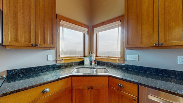 kitchen with a sink, dark stone countertops, and brown cabinets