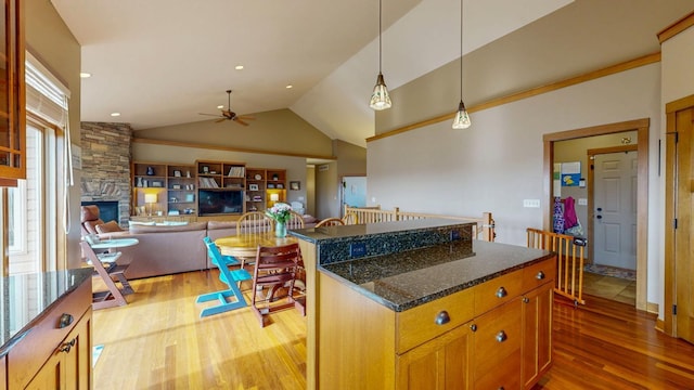 kitchen with a ceiling fan, vaulted ceiling, hanging light fixtures, and light wood finished floors