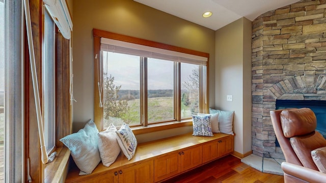 living area featuring a fireplace, vaulted ceiling, wood finished floors, and a wealth of natural light