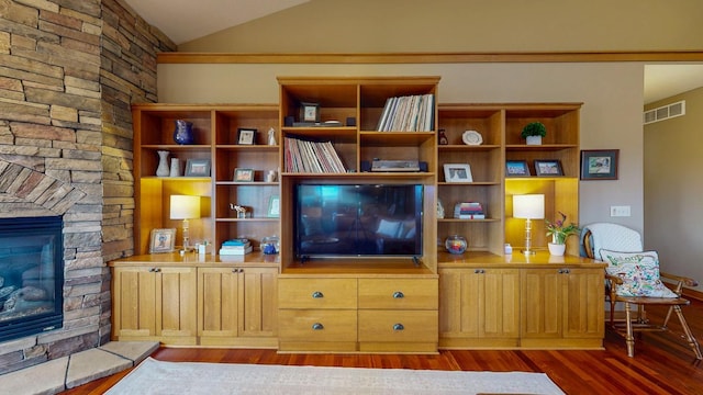 living area featuring a fireplace, vaulted ceiling, wood finished floors, and visible vents