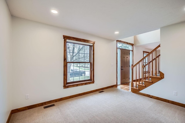 entrance foyer with carpet flooring, baseboards, visible vents, and stairs