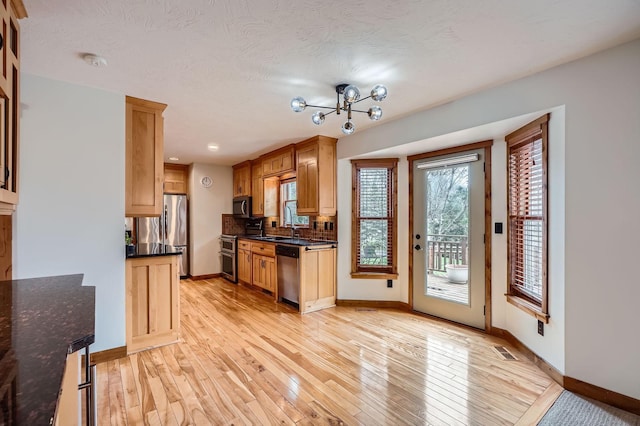 kitchen featuring appliances with stainless steel finishes, a sink, light wood-style flooring, baseboards, and visible vents