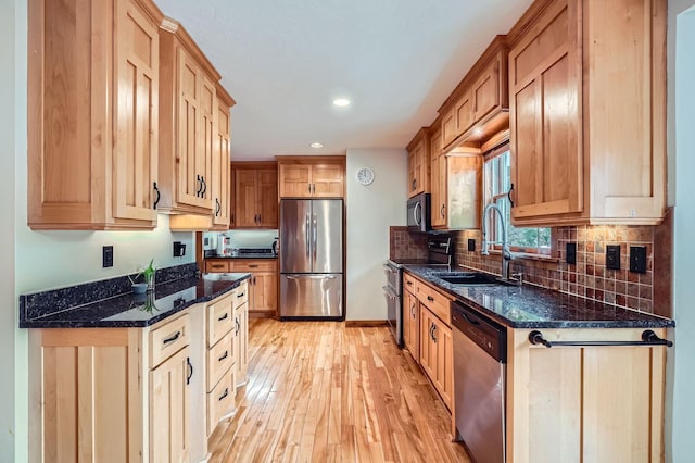kitchen with backsplash, appliances with stainless steel finishes, a sink, light wood-style floors, and recessed lighting