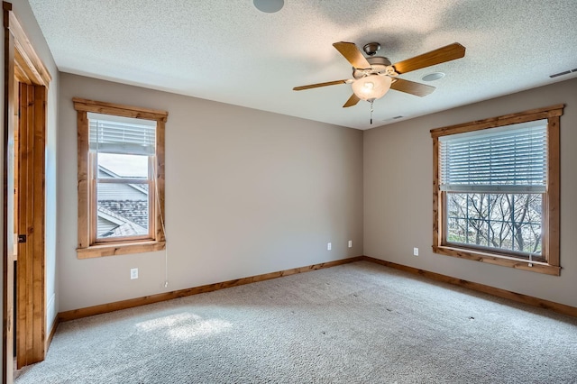 empty room featuring baseboards, ceiling fan, light carpet, and a textured ceiling