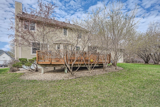 rear view of house with a chimney, a yard, and a deck
