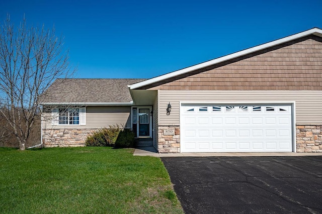 view of front of house with an attached garage, driveway, a front lawn, and stone siding
