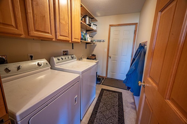 laundry room featuring a textured ceiling, cabinet space, and washing machine and clothes dryer