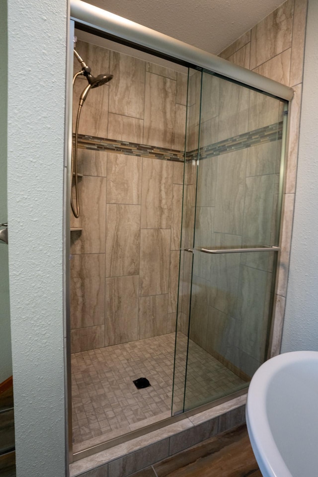 35873 Drumbeater Rd, Cohasset, MN 55721 - full bathroom with a textured wall, a stall shower, wood finished floors, a textured ceiling, and a soaking tub