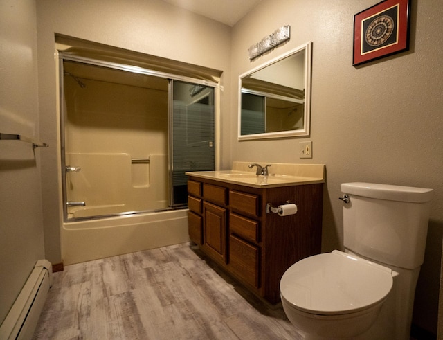 35873 Drumbeater Rd, Cohasset, MN 55721 - full bathroom with a baseboard radiator, wood finished floors, toilet, vanity, and shower / bath combination with glass door