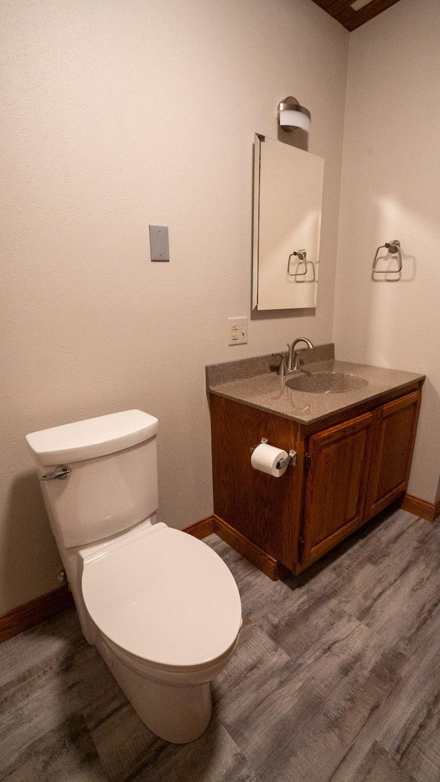35873 Drumbeater Rd, Cohasset, MN 55721 - half bathroom featuring wood finished floors, baseboards, toilet, and vanity