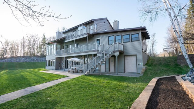 35873 Drumbeater Rd, Cohasset, MN 55721 - rear view of house with a chimney, a balcony, a patio, a lawn, and stairs