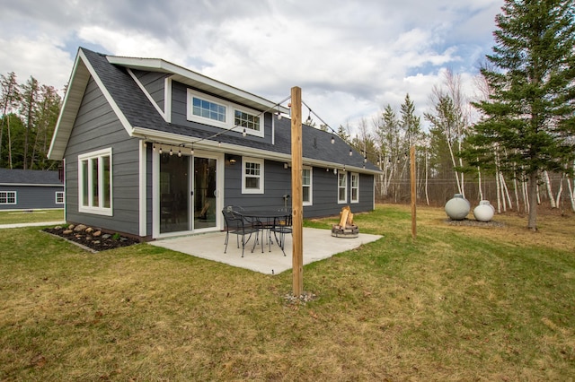 back of property featuring a yard, a shingled roof, and a patio area