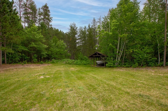 29133 Neighborly Dr, Laporte, MN 56461 - view of grassy yard featuring a carport and a view of trees