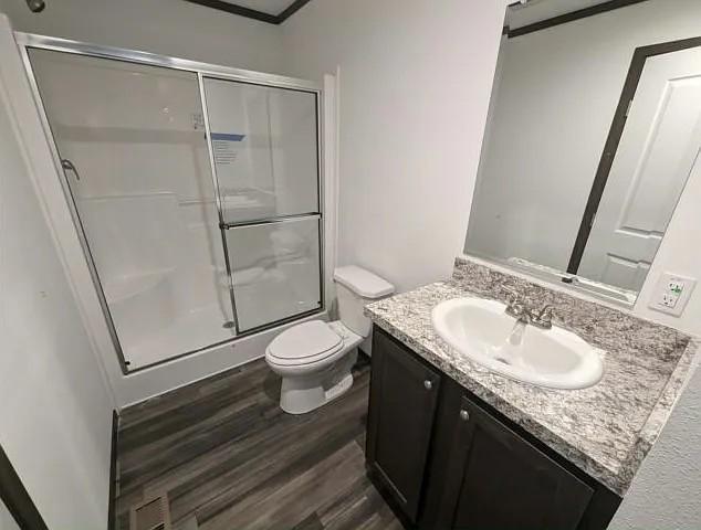 133 Maple Dr, Mankato, MN 56001 - bathroom with a stall shower, wood finished floors, vanity, toilet, and ornamental molding