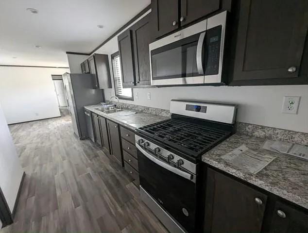 133 Maple Dr, Mankato, MN 56001 - kitchen with dark cabinets, a sink, appliances with stainless steel finishes, and wood finished floors