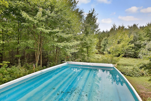 view of swimming pool with a forest view