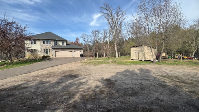 view of yard featuring an outdoor structure, aphalt driveway, and a shed