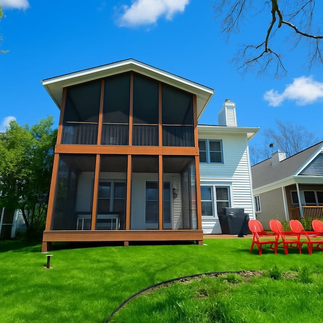 rear view of house featuring a sunroom, a chimney, and a yard